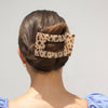 Person with a leopard print hair clip in their bun against a plain background