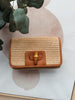 Woven handbag with brown leather accents on a light background