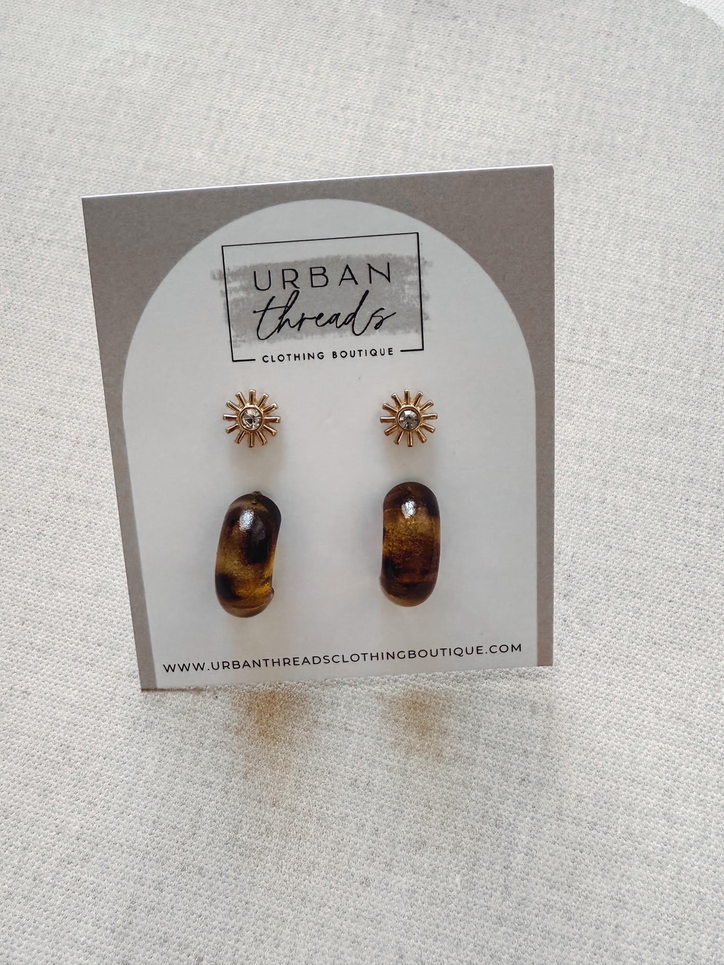 Pair of tortoiseshell stud earrings on a 'Urban Threads' branded card.
