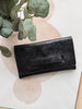 Black leather wallet on a light background with green leaves