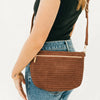 Brown woven handbag worn over shoulder on a plain background