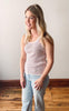 Woman wearing a striped tank top and jeans in a bright room.