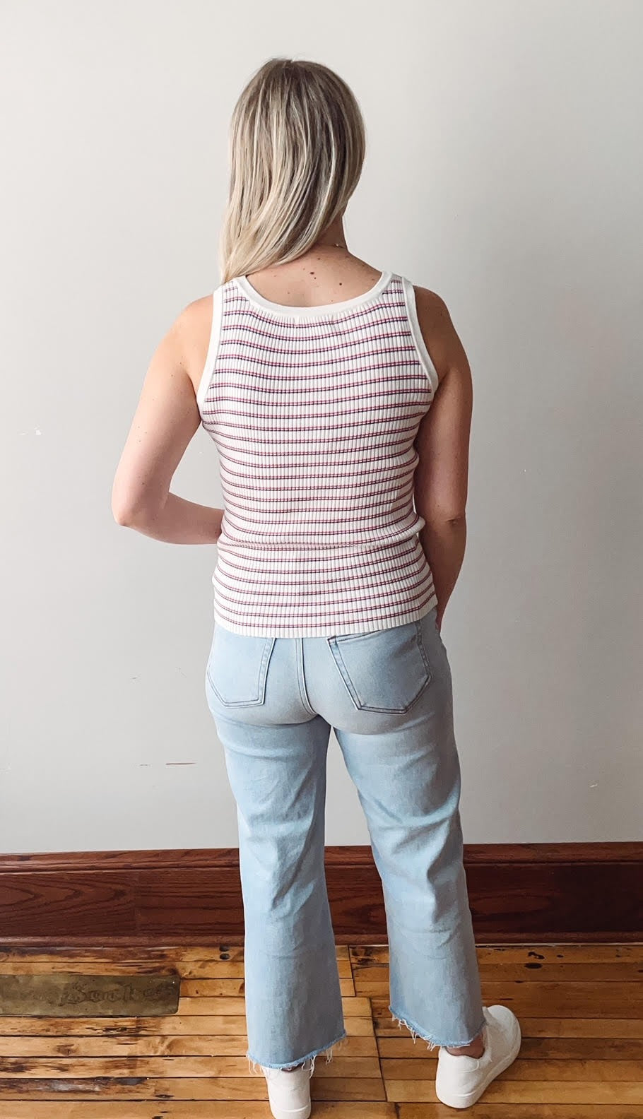 Person wearing a striped tank top and light blue jeans from the back.