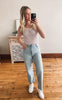 Woman in striped tank top and jeans taking a mirror selfie in a room.