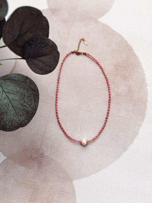 Necklace with a pearl pendant on a textured surface with leaves