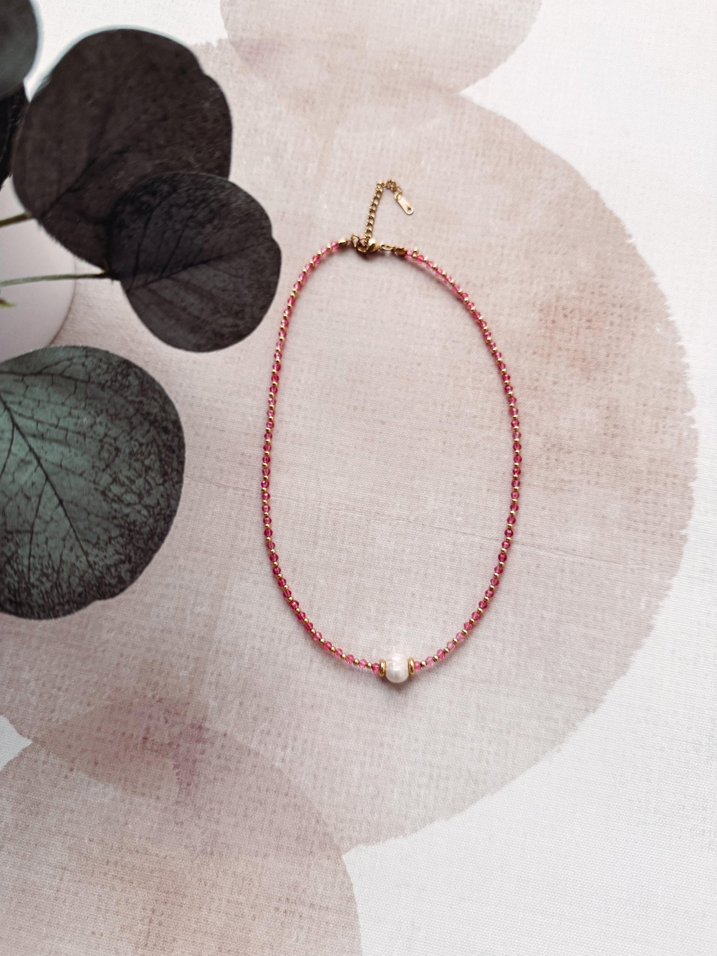 Necklace with a pearl pendant on a textured surface with leaves