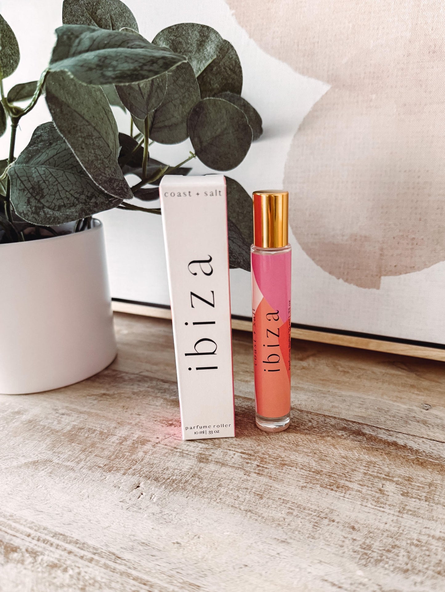 ibiza perfume bottle and packaging on a wooden surface with a plant in the background