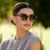 Woman wearing sunglasses with a blurred green background