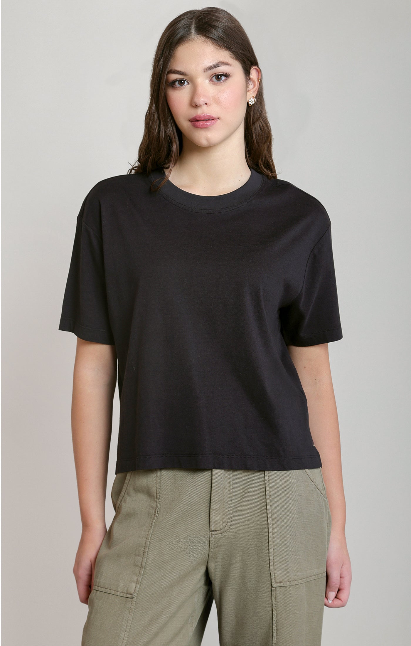Person wearing a black t-shirt and green pants on a plain background