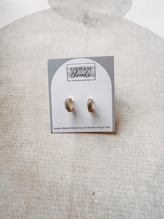 Pair of earrings on a card with 'Urban Threads' branding on a textured surface.