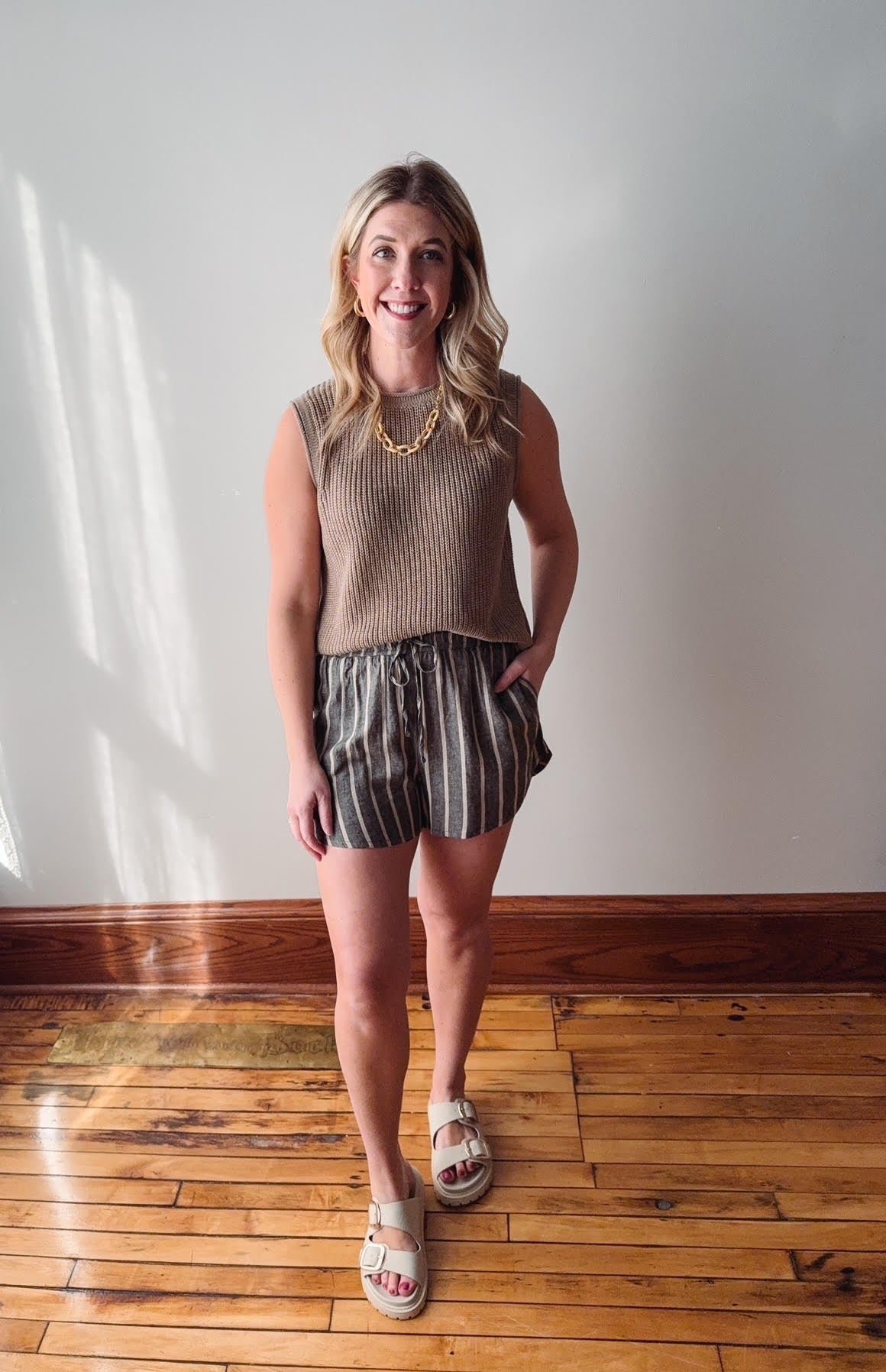 Woman standing in a room with wooden flooring and white walls
