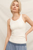 Woman wearing a white tank top and blue skirt against a beige background