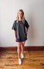 Woman wearing a dark gray oversized t-shirt and shorts on a wooden floor.
