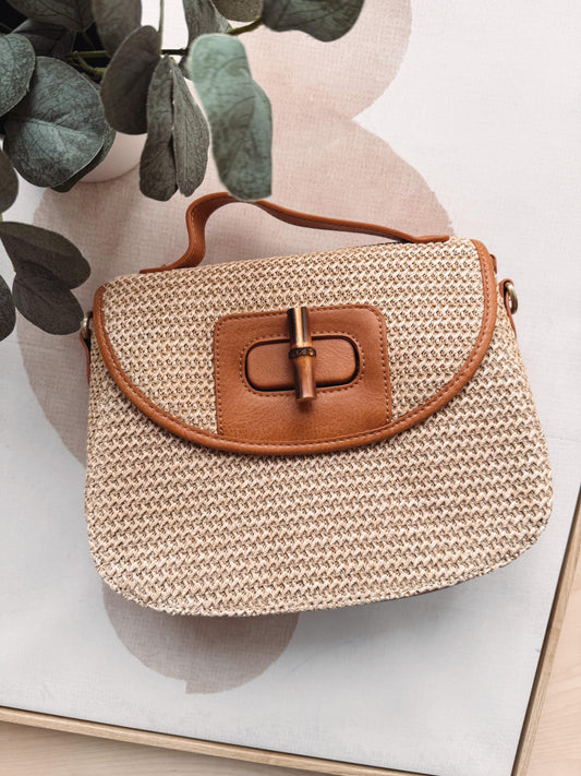 Woven handbag with brown leather buckle on a light background