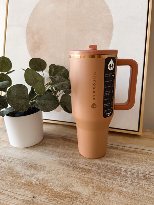 Ceramic mug with handle on a wooden surface next to a plant