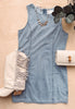 Denim dress with beige boot, handbag, and necklace on a wooden surface