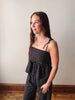 Woman wearing a black polka dot dress standing against a plain wall.