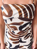 A close-up of a person wearing a strapless dress with a bold abstract animal-inspired print in brown, black, and cream.