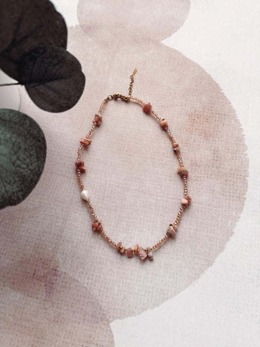 Necklace with brown beads on a textured beige surface