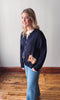 Woman wearing a navy cardigan with a small dog design on a wooden floor.