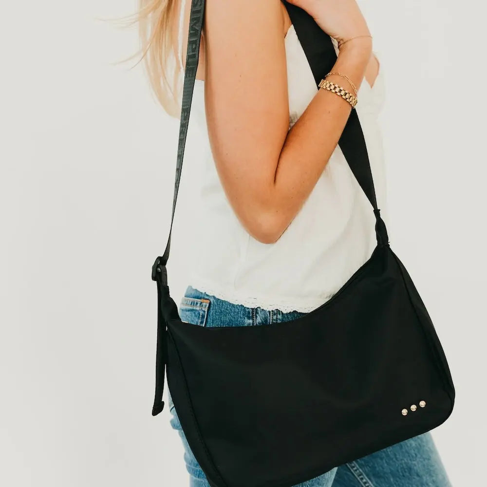Person wearing a black shoulder bag on a plain background