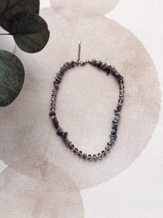 Necklace with gray beads on a beige fabric background