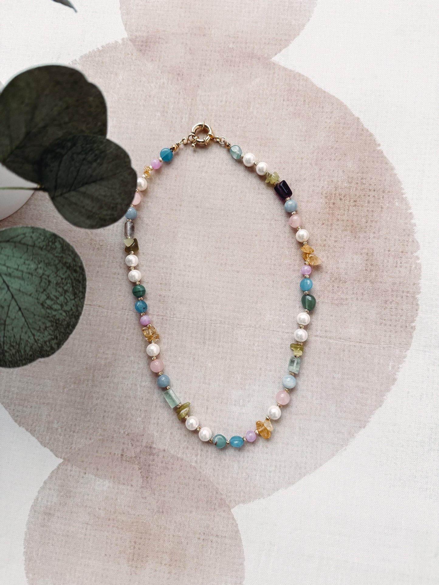 Necklace with multicolored beads on a textured surface with leaves