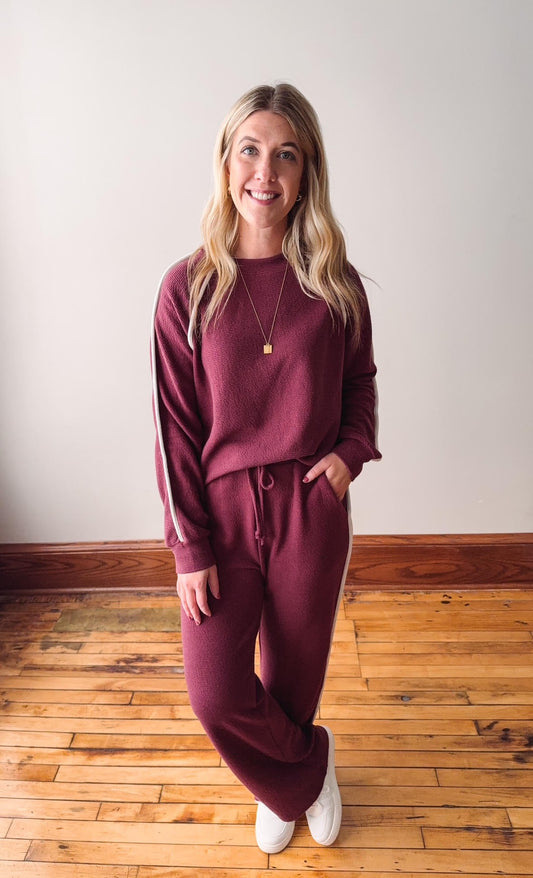 Woman wearing a burgundy loungewear set on a wooden floor.