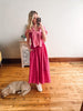 Woman in a pink dress taking a mirror selfie with a dog on the floor.
