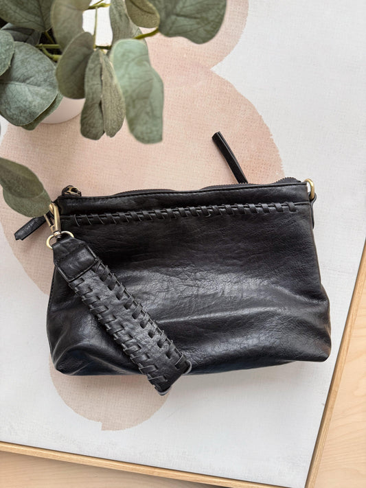Black leather clutch bag with braided strap on a light background