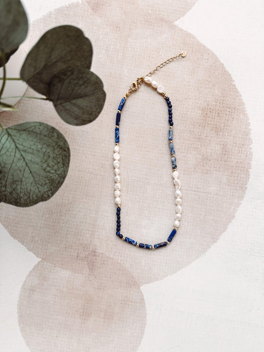 Necklace with blue and white beads on a beige fabric background