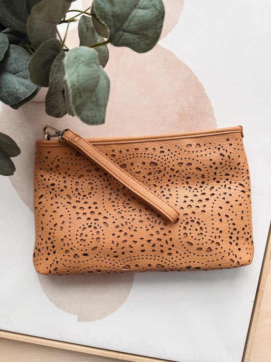 Brown textured clutch bag on a light background with green leaves.
