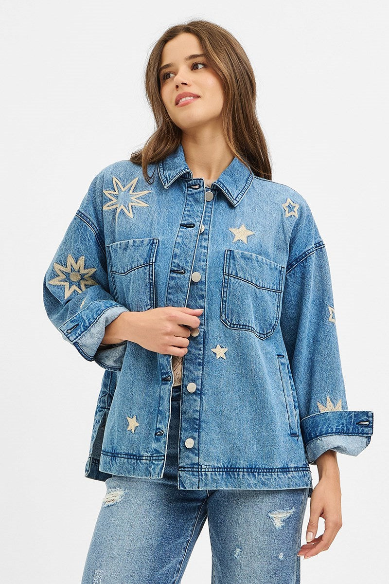 Woman wearing a denim jacket with star patterns on a light blue background