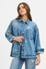 Woman wearing a denim jacket with star patterns on a light blue background