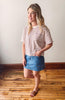 Woman in striped shirt and denim skirt standing on wooden floor