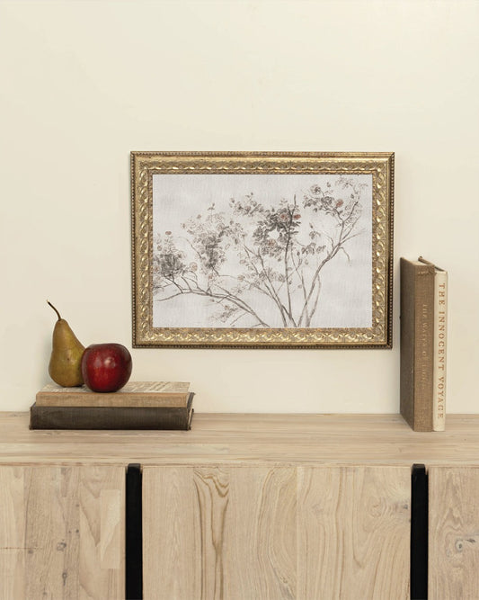 Framed artwork on a wooden shelf with books and a pear