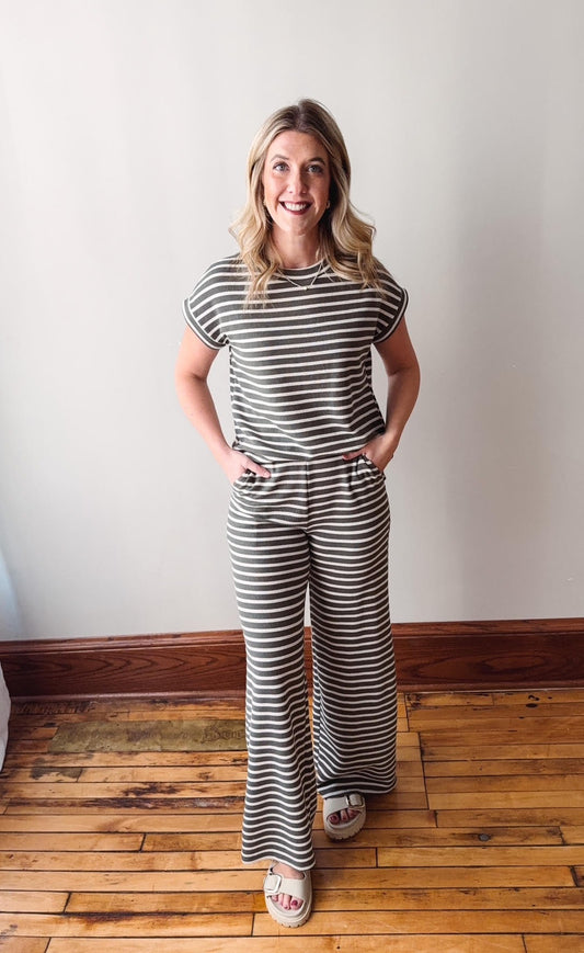 Woman wearing a black and white striped outfit standing on a wooden floor.