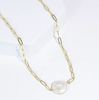 Gold chain necklace with a large pearl pendant on a white background