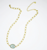 Gold chain necklace with a green gemstone on a white background