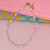 Necklace with pearls and gold accents on a pink background