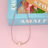 Necklace with a pearl pendant on a pink surface with 'AMALFI' branding.