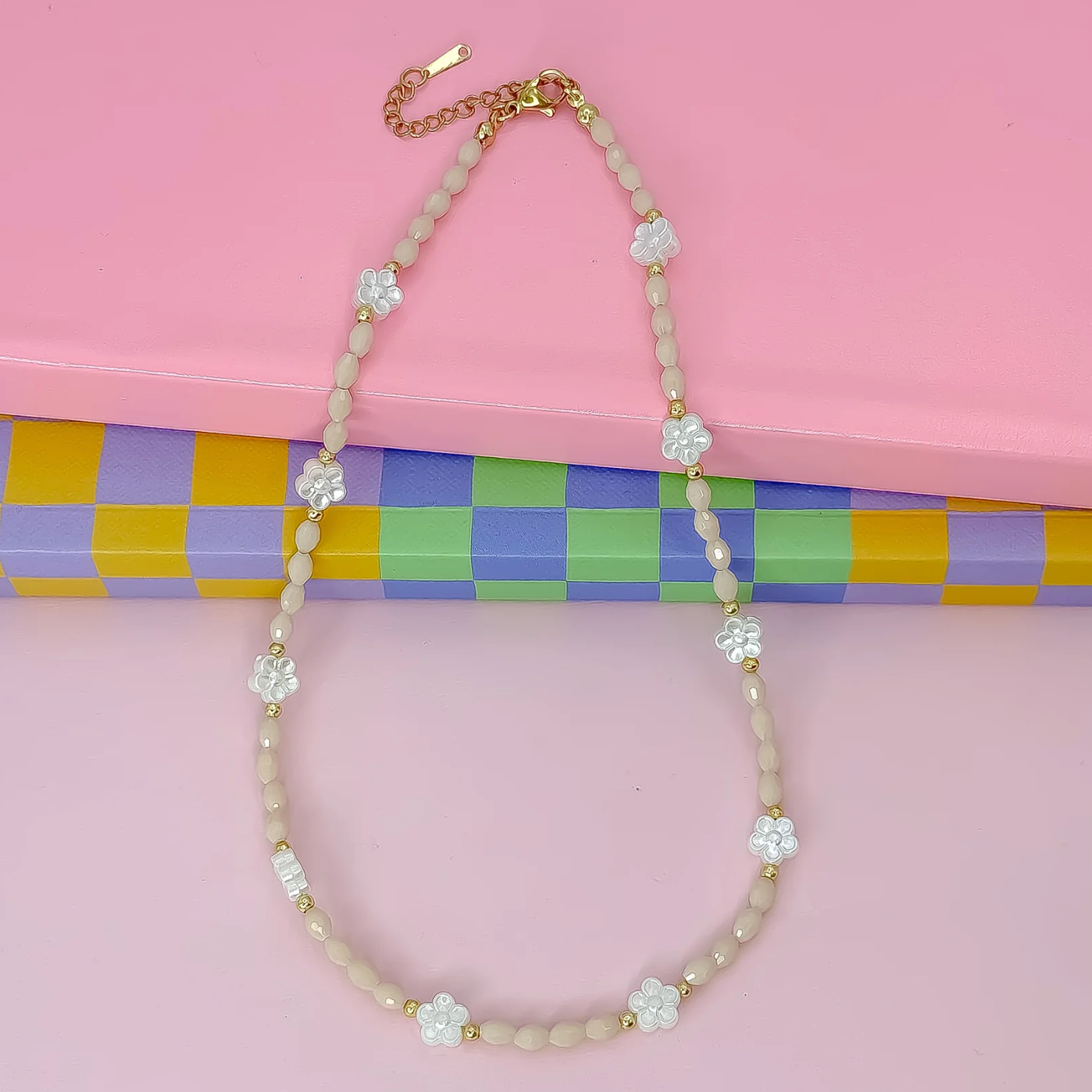Necklace with floral beads on a pink background