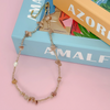 Necklace with stone beads on a pink surface with 'AMALFI' branding.