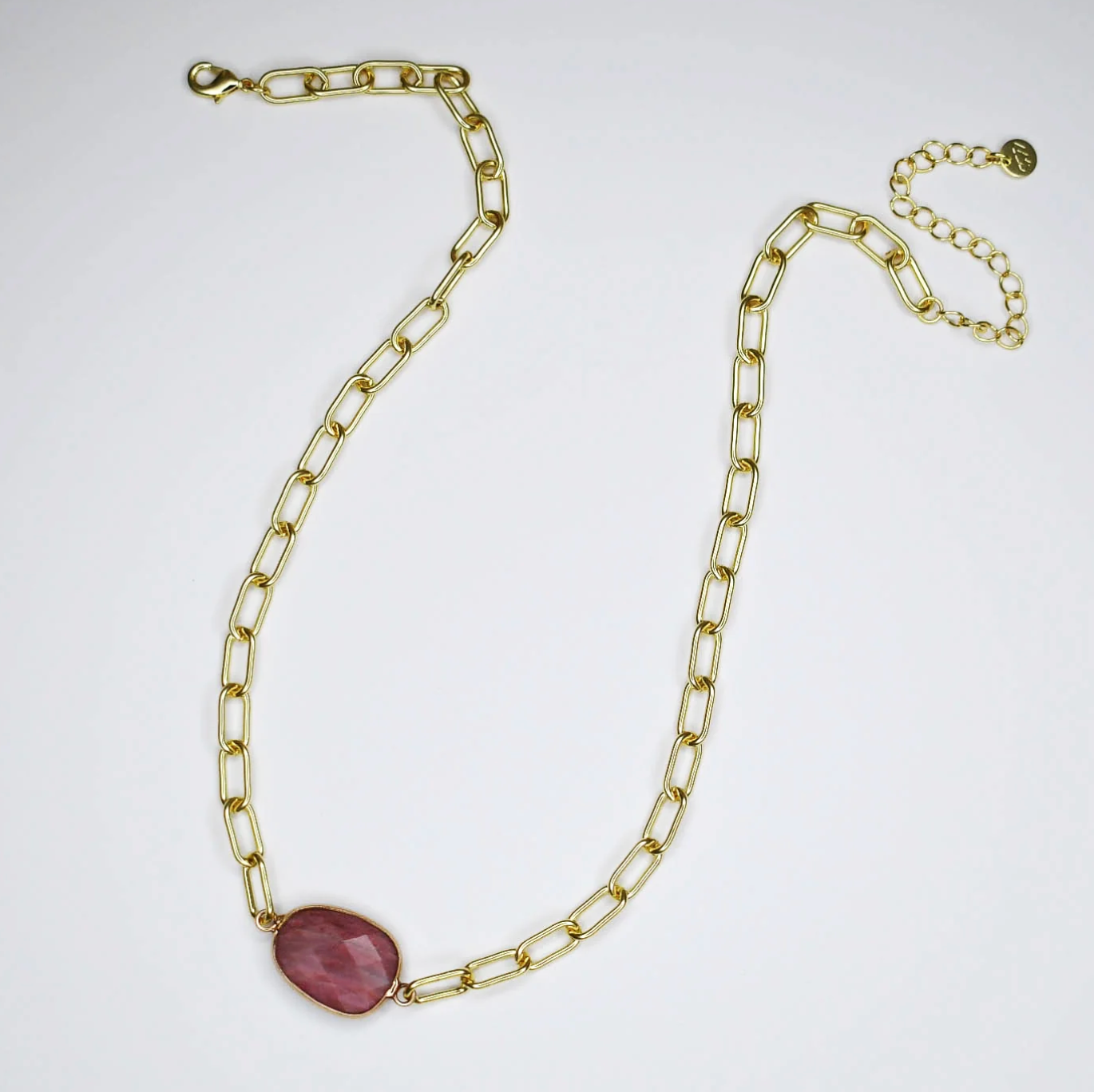 Gold chain necklace with a pink stone on a white background
