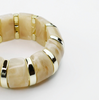 Beige bracelet with gold accents on a white background
