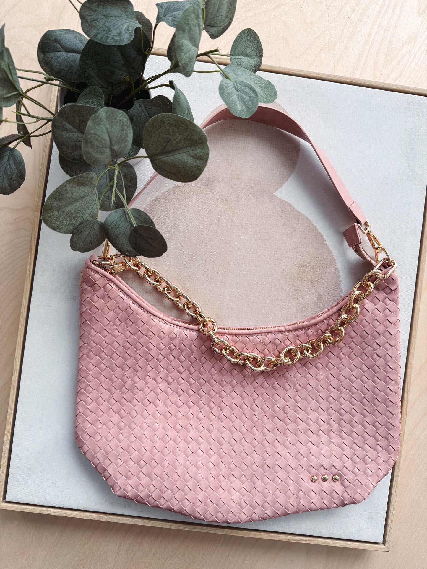 Pink handbag with gold chain strap on a light background