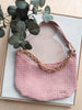 Pink handbag with gold chain strap on a light background
