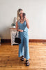 Woman taking a mirror selfie wearing a blue jumpsuit in a room with wooden flooring.