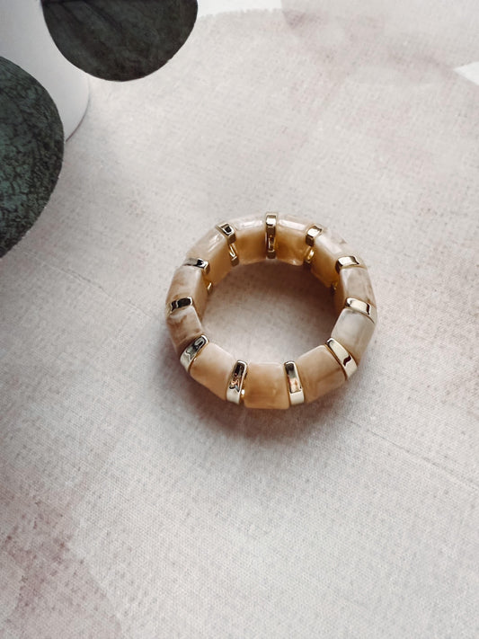Beige beaded ring on a textured surface