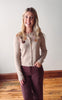 Woman wearing a taupe cardigan with floral embellishments against a plain wall.